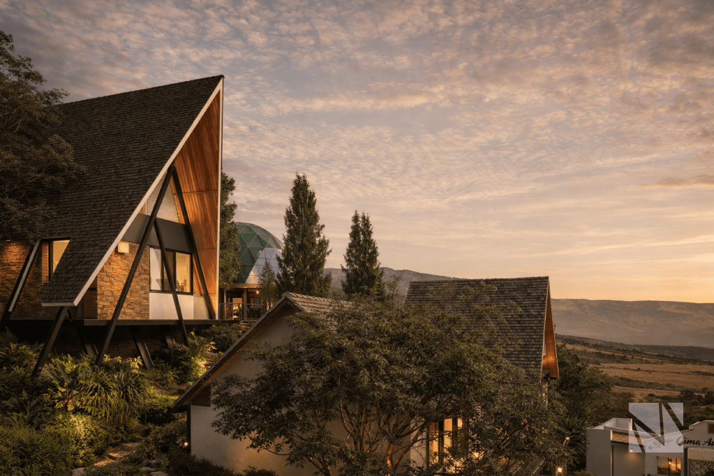 Complejo turístico de cabañas A-frame y domos geodésicos en paisaje montañoso.