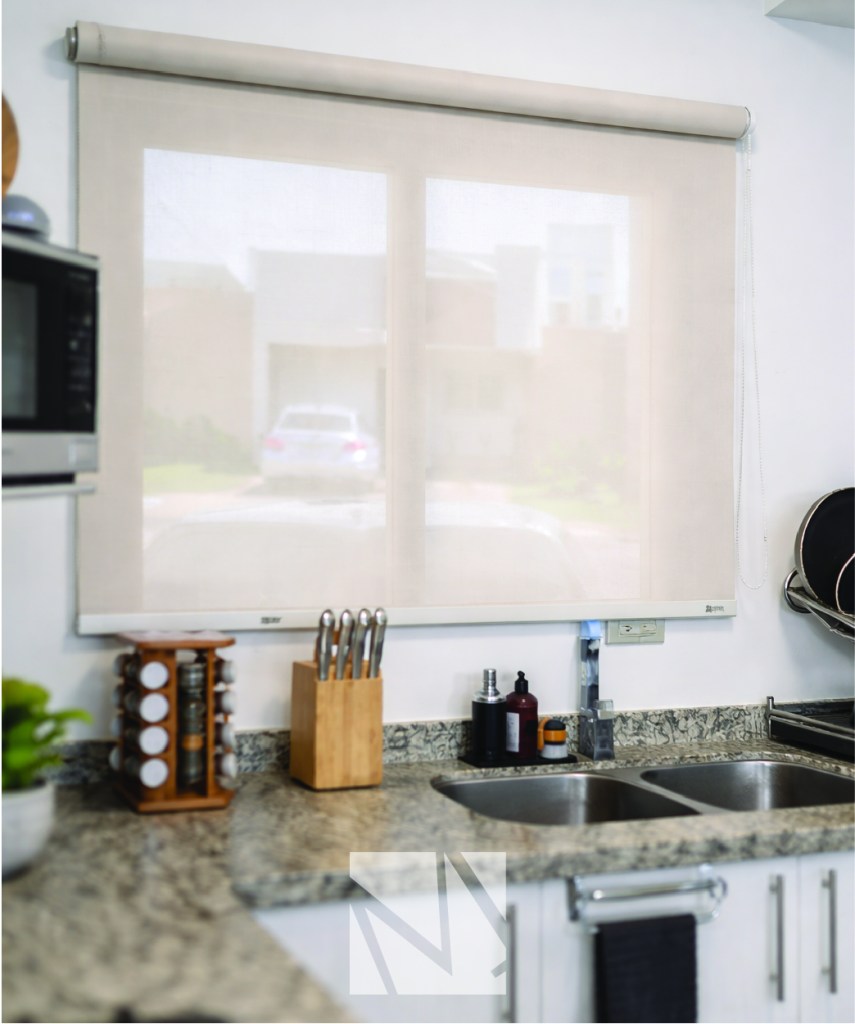 Cocina moderna minimalista con encimera de granito, fregadero doble de acero inoxidable y luz natural entrando por ventana con cortina roller.